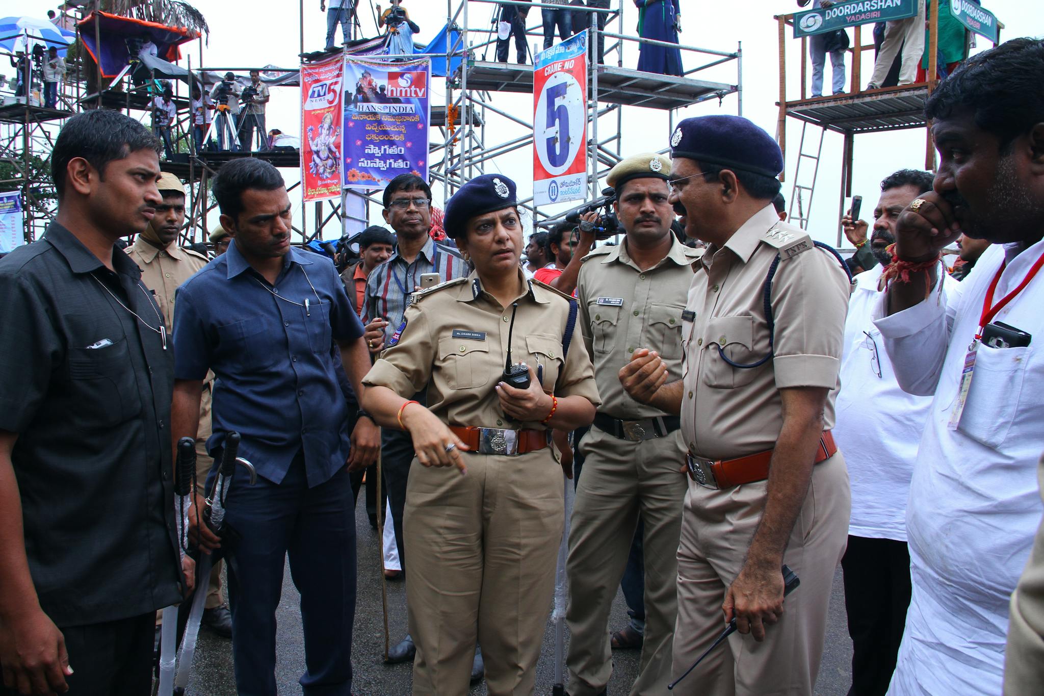 Police officers engaged in a strategic discussion at an outdoor event setup with visible media coverage.